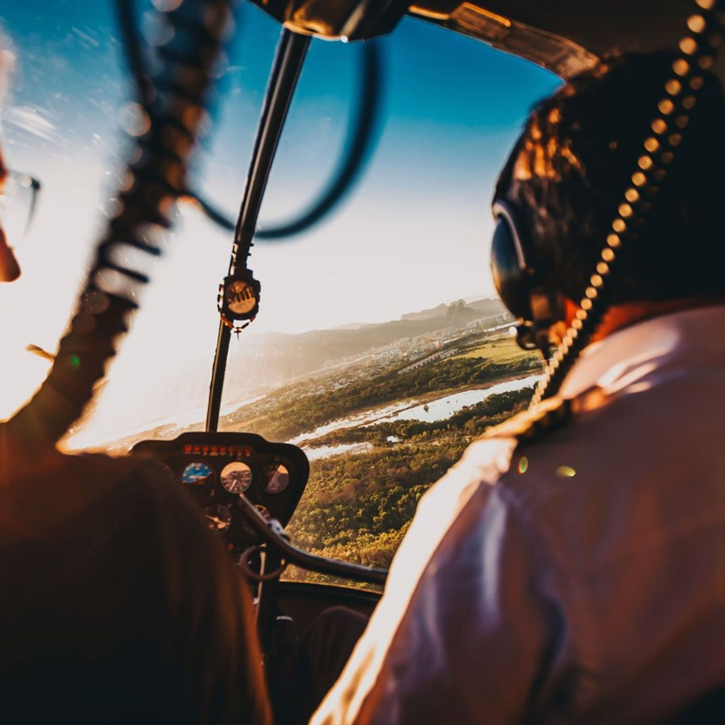 Billede af to piloter i en helikopter, der flyver over et naturskønt landskab