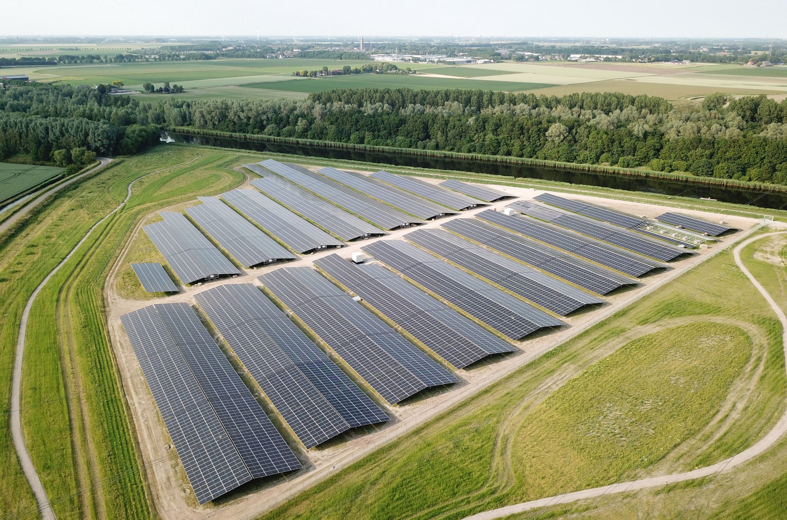 En stor solcellepark omgivet af grønne marker og skovområder